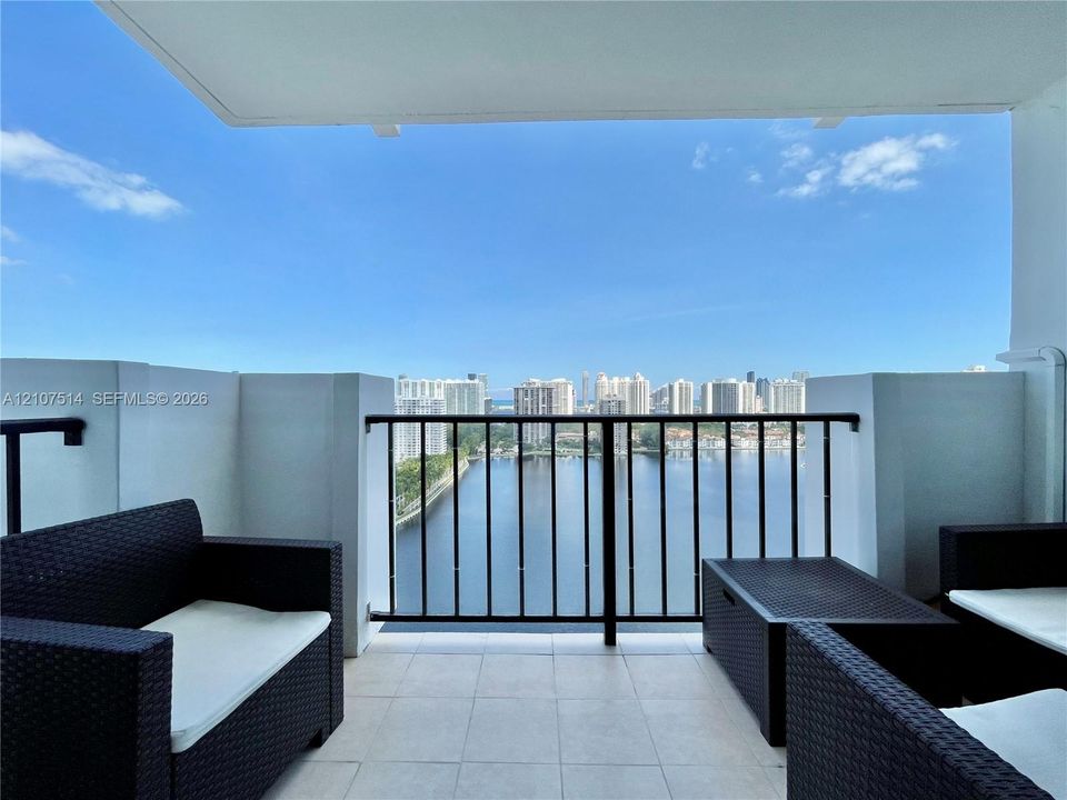 Private balcony featuring tiled flooring, solid wall partitions, and a black metal railing