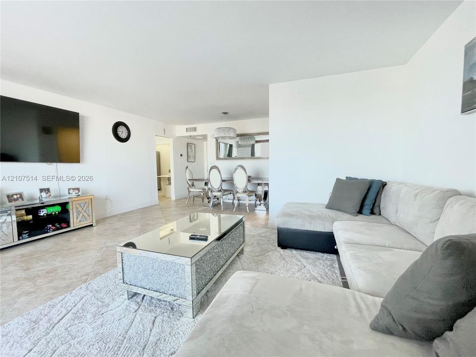 Open-concept floor plan featuring neutral tile flooring, smooth wall finishes, and a dedicated dining area with a modern drum-style pendant light fixture