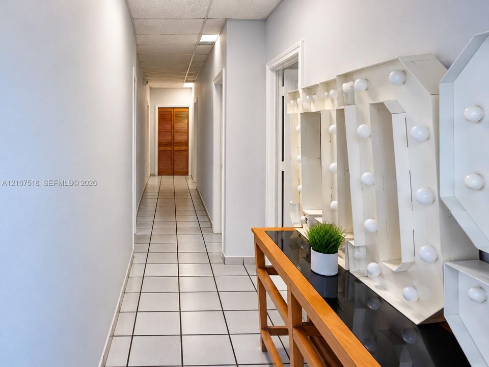 Hallway featuring square tile flooring, neutral wall finishes, and wood-finish bifold closet doors