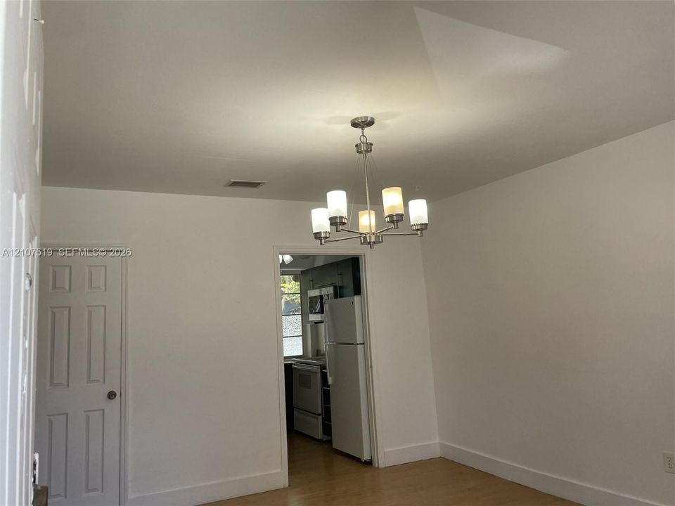 Interior space featuring wood-finish flooring, a multi-arm chandelier with frosted glass shades, and a six-panel door