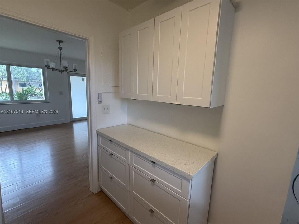 Shaker-style cabinetry with white finish, light-toned composite countertop, and wood-finish flooring