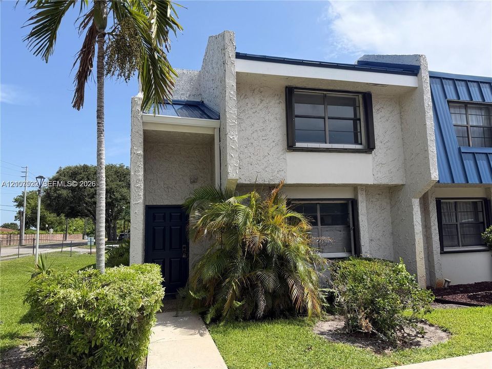 Multi-level exterior featuring a textured stucco finish, metal roof accents, and dark-framed windows