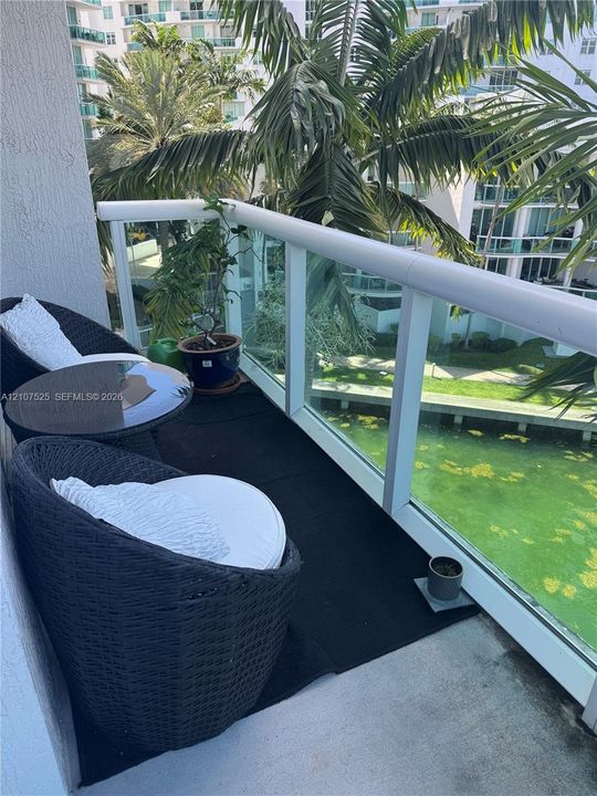 Covered balcony featuring white structural framing and clear glass panel railings