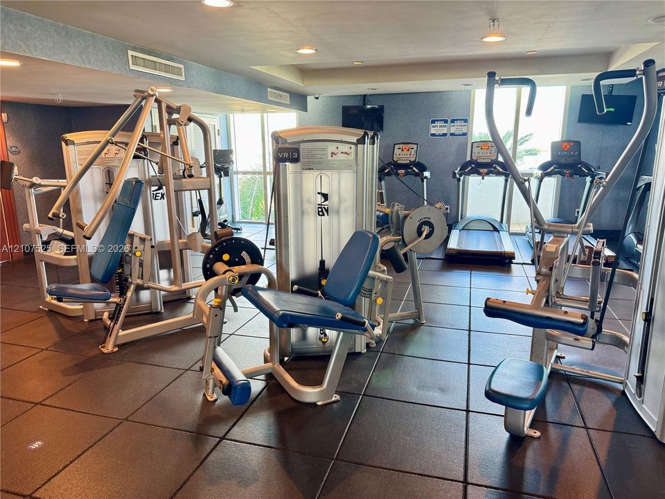 Fitness room featuring high-impact rubber flooring, recessed ceiling lighting, and multiple strength training and cardiovascular machines