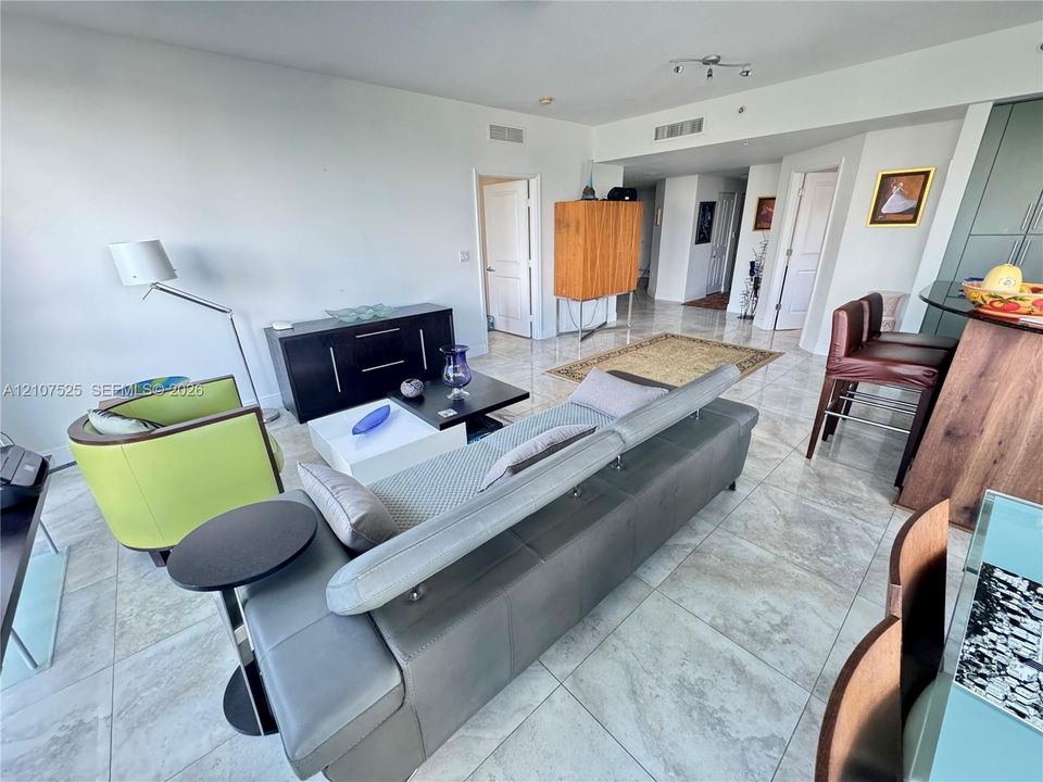 Open-concept living area featuring large-format tile flooring, high ceilings with recessed lighting, and white interior doors