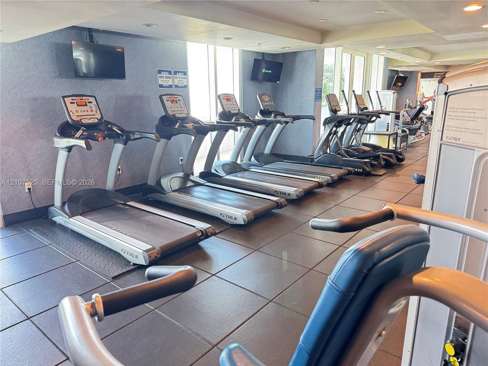 Fitness center featuring rows of commercial-grade treadmills, modular strength training equipment, and impact-resistant rubberized flooring