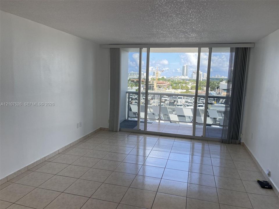 Ceramic tile flooring, floor-to-ceiling sliding glass doors, and a private balcony with a metal railing