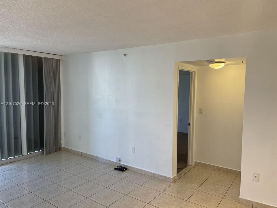 Interior space featuring neutral tile flooring, vertical window blinds, and a flush-mount ceiling light fixture