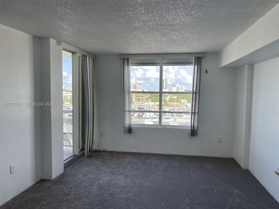 Interior space featuring grey wall-to-wall carpeting, large multi-pane windows, and a sliding glass door