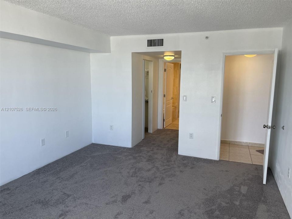 Neutral-toned carpeting, smooth-finish walls, ceiling-mounted lighting, and solid core interior doors