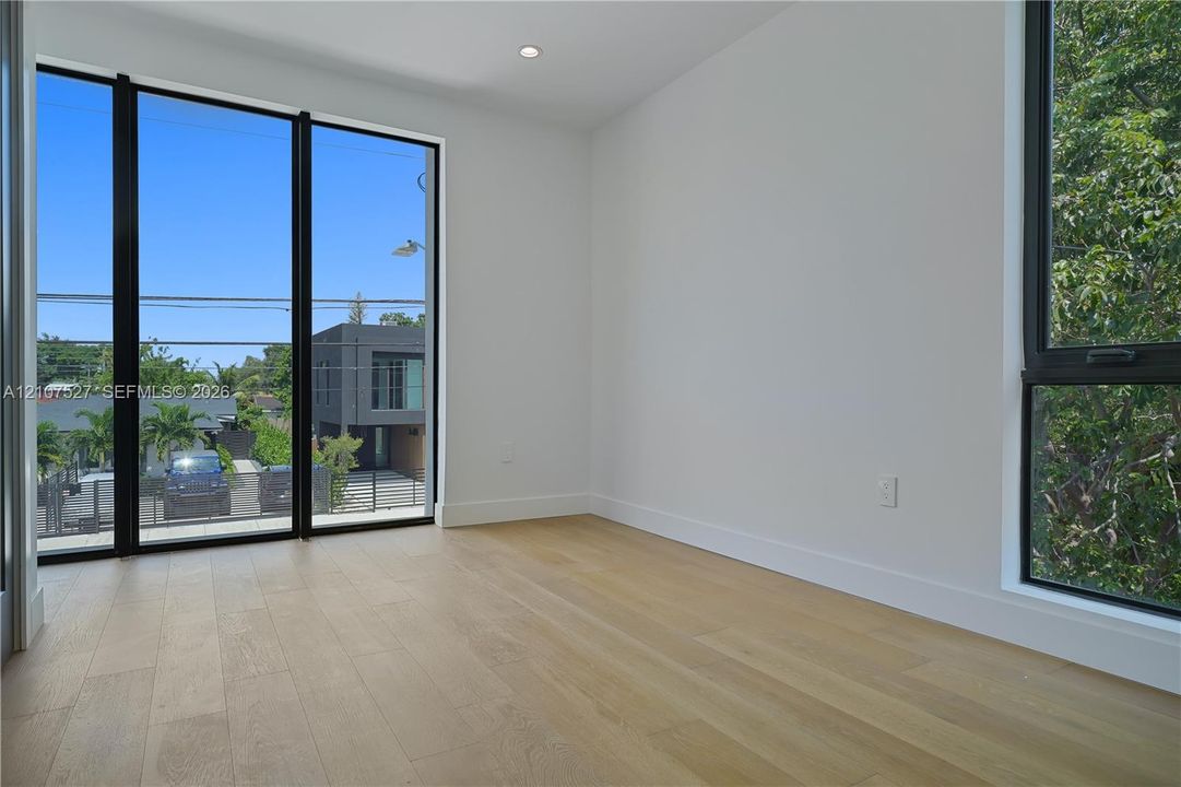 Interior space featuring wood-finish flooring, floor-to-ceiling windows with black frames, and recessed lighting