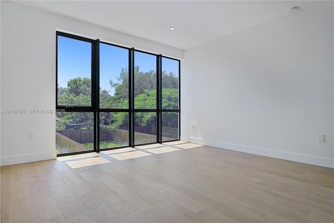 Floor-to-ceiling black-framed windows, wood-finish flooring, and recessed ceiling lighting