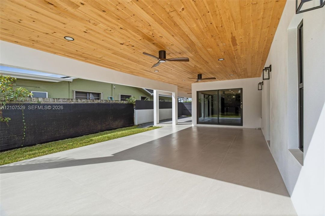 Spacious interior featuring large-format tile flooring, recessed lighting, a modern drum-style flush mount ceiling fixture, and black-trimmed windows