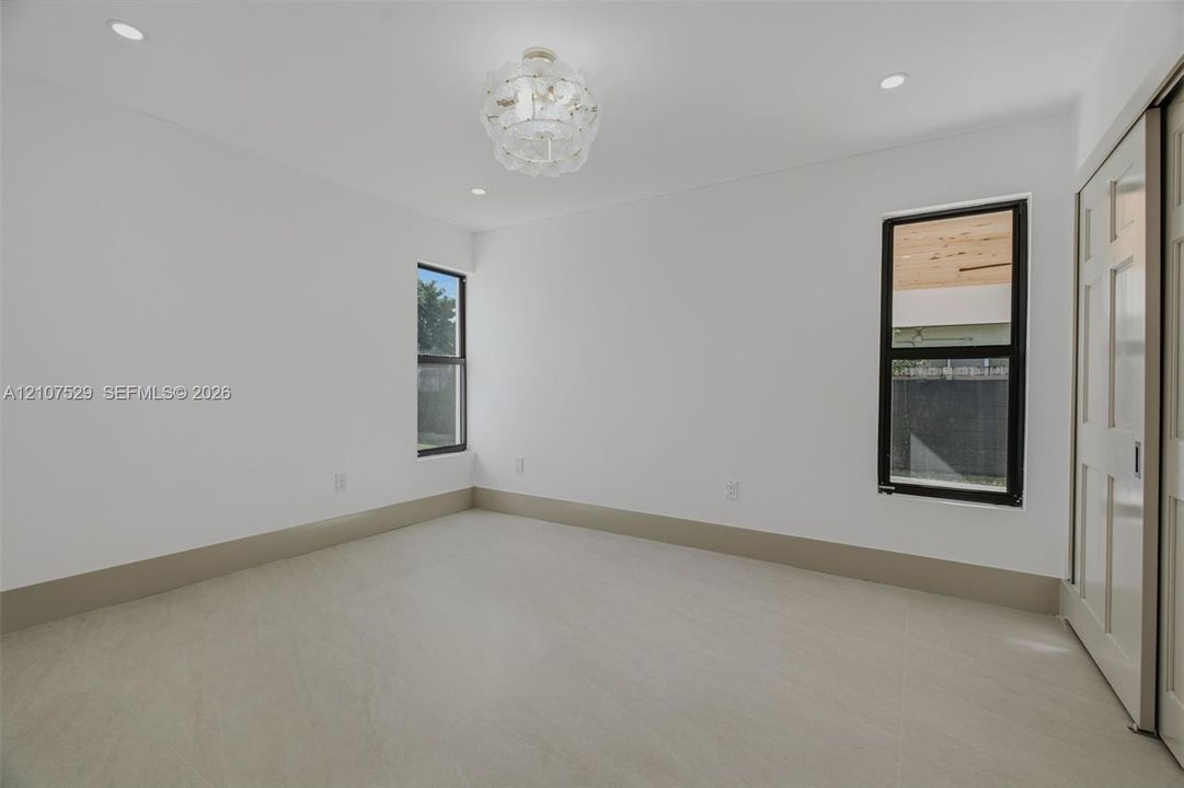 Expansive backyard featuring a grass lawn, mature trees, and perimeter privacy fencing