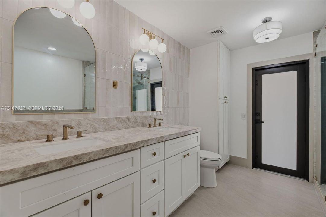 Neutral-toned tile flooring, recessed lighting, ornate central pendant fixture, black-framed windows, and built-in closet with panel doors