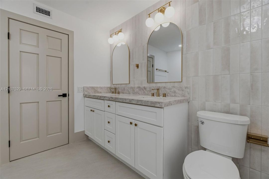 Neutral-toned tile flooring, multi-pane sliding closet doors, decorative multi-tiered pendant lighting, and recessed ceiling illumination