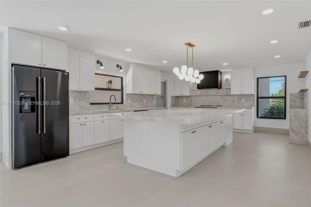 Kitchen featuring white cabinetry, stone-surface countertops, full-height stone backsplash, matte black appliances, and recessed lighting