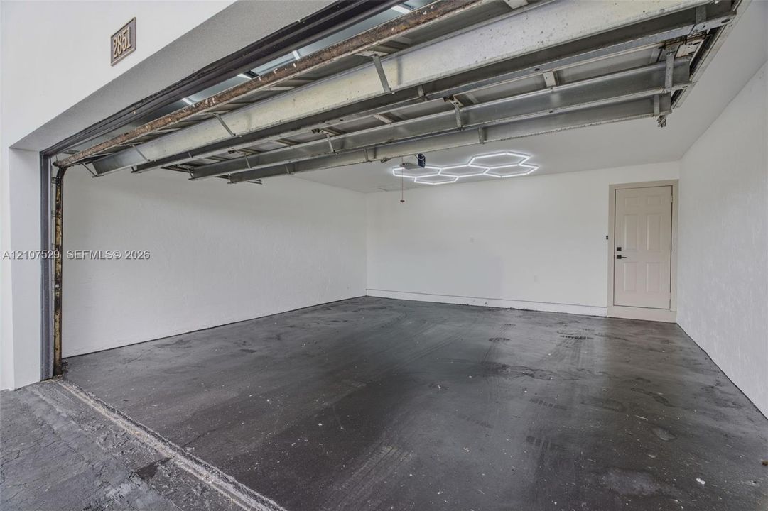 Multi-car garage featuring a concrete floor, finished white walls, and a hexagonal LED ceiling fixture