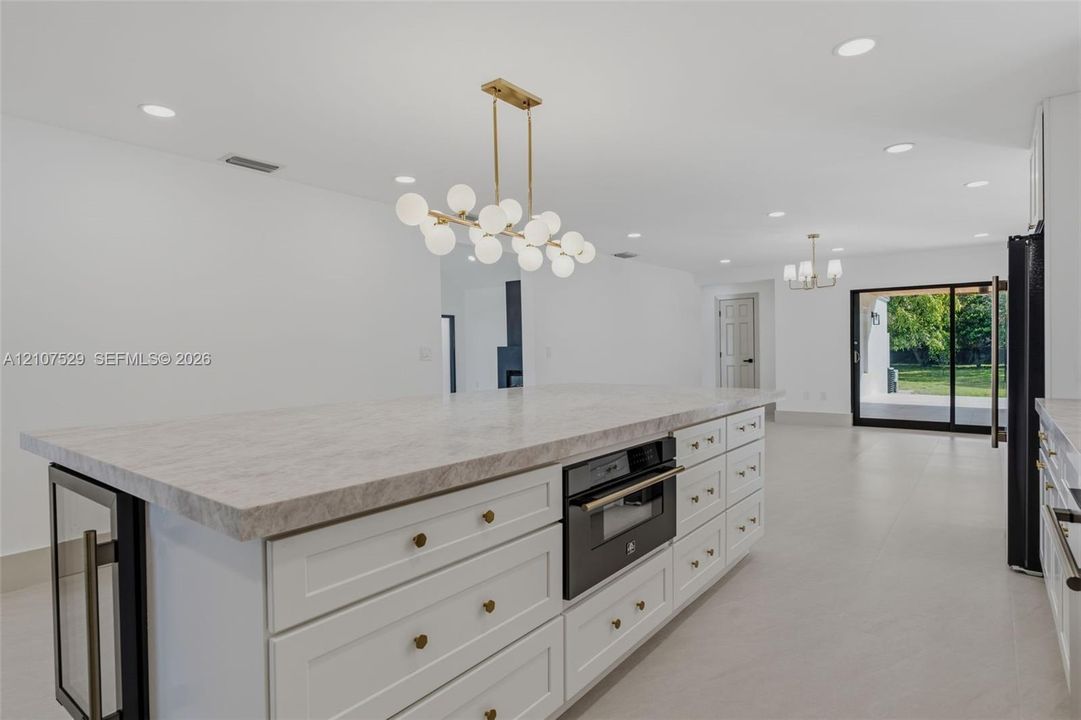 Covered patio featuring a wood-plank ceiling, ceiling fan, large sliding glass doors, and light-toned tile flooring