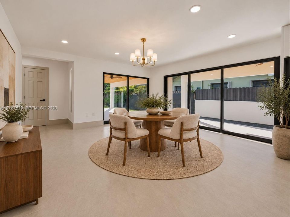 Neutral-toned interior featuring large-format flooring, recessed lighting, a multi-arm chandelier, and expansive sliding glass doors