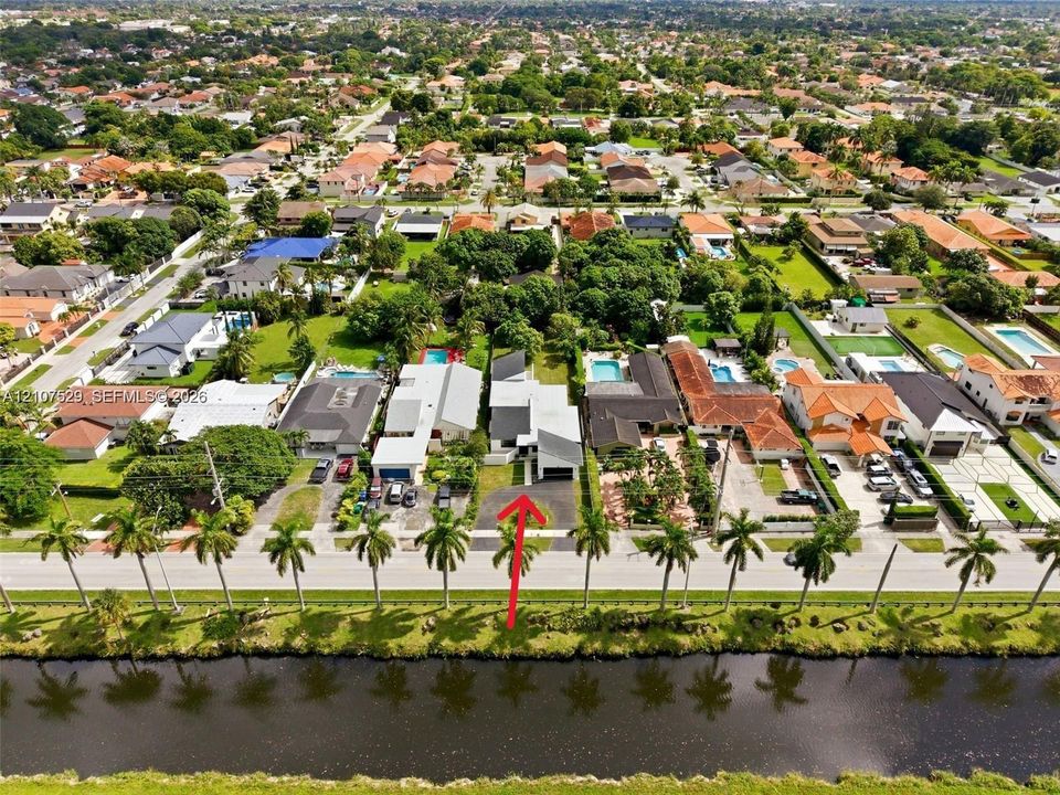 Expansive residential grounds featuring two inground swimming pools, manicured lawn, established perimeter hedging, and mature trees