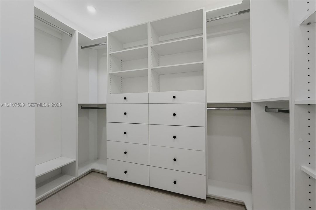 Neutral-toned room featuring a tiered crystal chandelier, wood-finish flooring, recessed lighting, double-panel sliding closet doors, and black-framed windows
