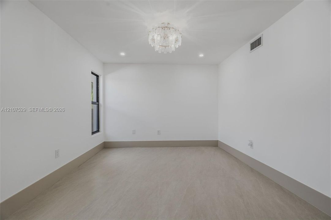 Neutral wall color, light-toned hard-surface flooring, black-framed windows, and a decorative tiered crystal chandelier