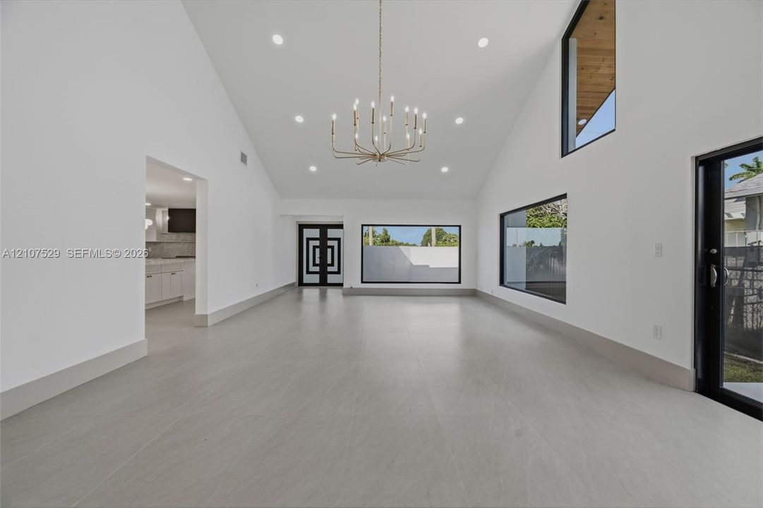 Open-concept kitchen featuring white cabinetry, a center island with stone-finish countertops, recessed lighting, and expansive sliding glass doors