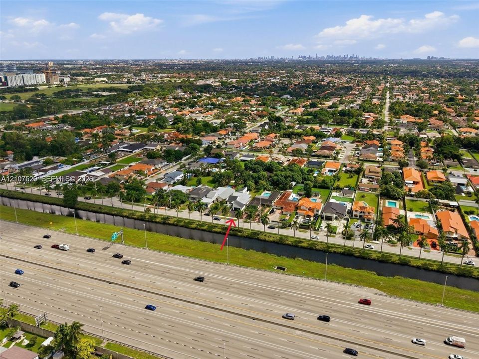 Aerial perspective of a residential property featuring an in-ground swimming pool, concrete pool deck, and mature landscaping