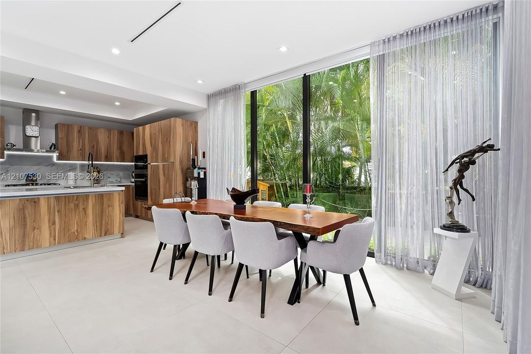 Modern kitchen featuring custom wood-finish cabinetry, stone slab backsplash, integrated built-in appliances, and floor-to-ceiling glass windows
