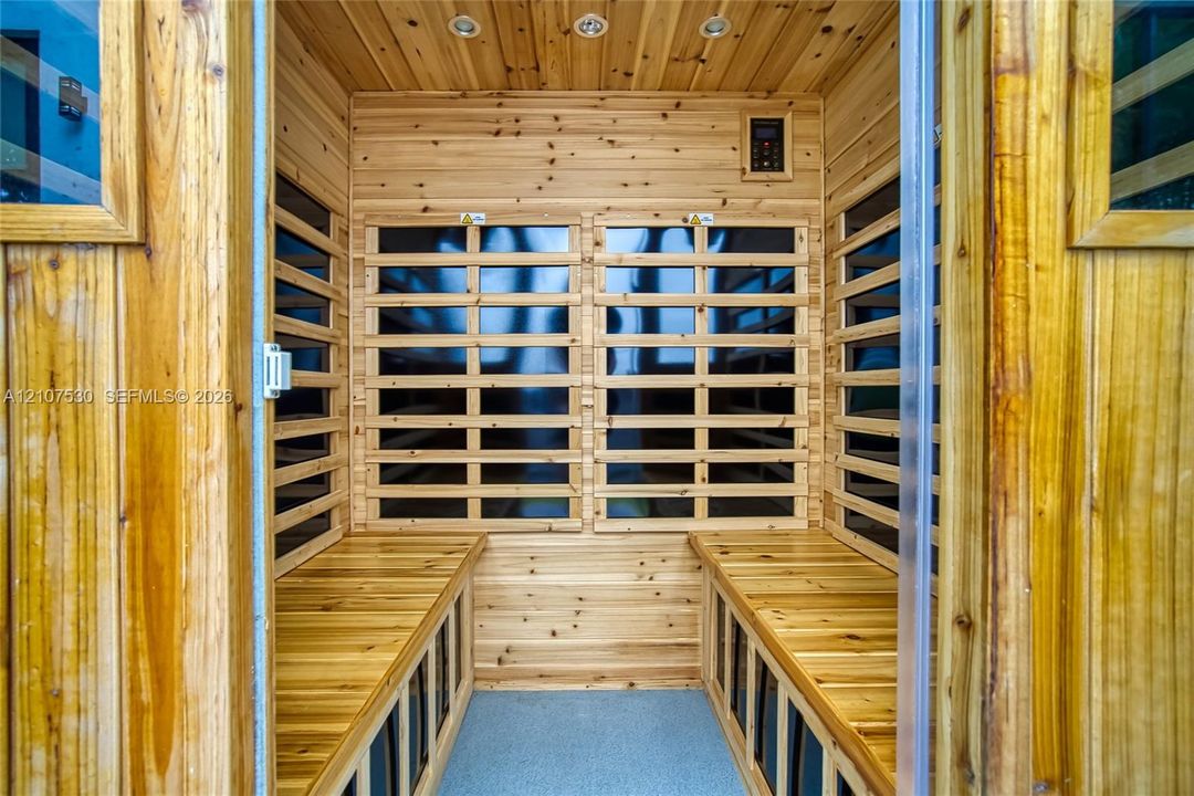 Sauna featuring tongue-and-groove wood paneling, integrated bench seating, built-in digital controls, and recessed ceiling lighting
