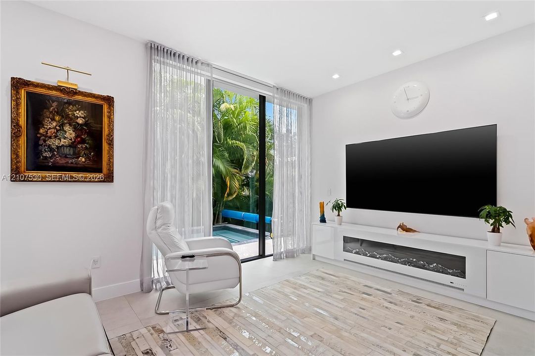 Living area featuring floor-to-ceiling glass sliding doors, built-in media cabinetry with integrated electric fireplace, and recessed lighting