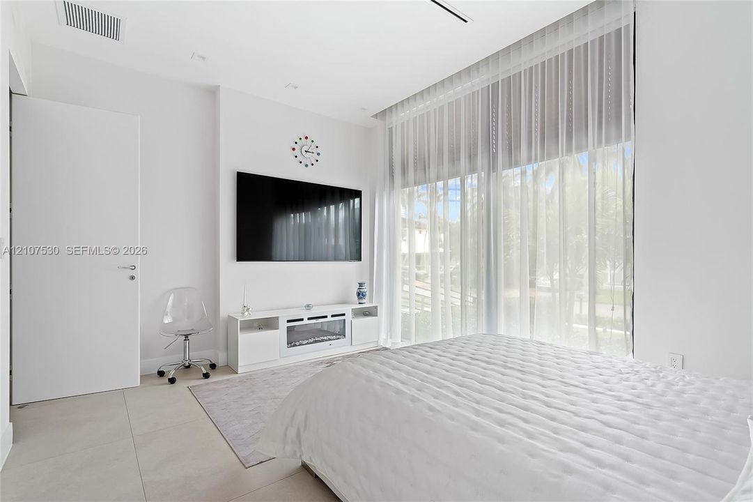 Floor-to-ceiling windows with floor-length treatments, large-format tile flooring, flush-mount ceiling lighting, and a crisp white interior finish