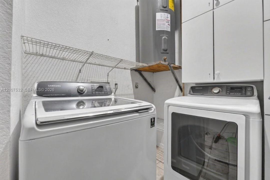 Utility area featuring white built-in cabinetry, wire shelving, and a water heater