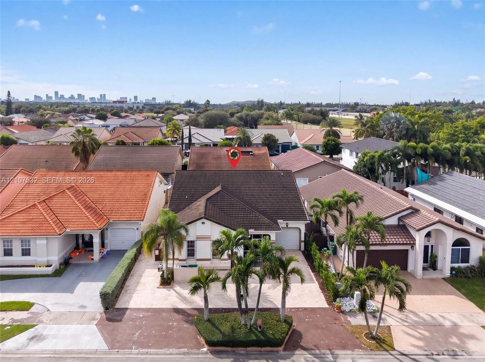 Single-story residence featuring a tile roof, paved driveway, one-car garage, and established palm tree landscaping