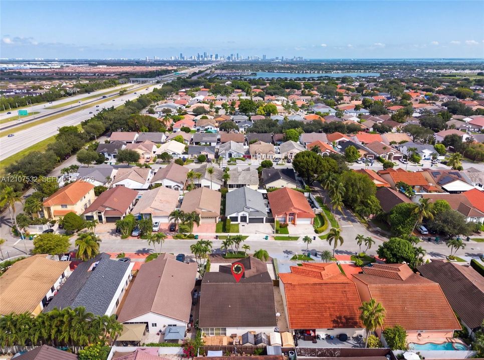 Aerial perspective of a residential property featuring a pitched shingle roof, mature perimeter landscaping, and a fenced rear yard