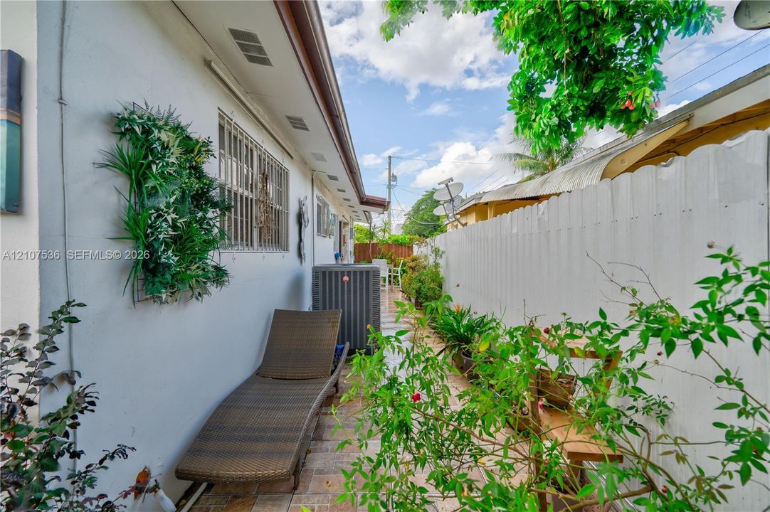 Side yard featuring paver flooring, white exterior wall, and perimeter wood fencing