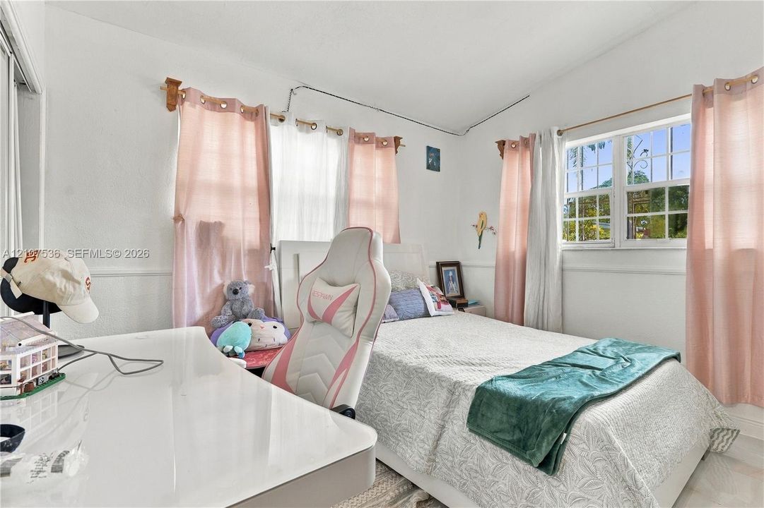 Bedroom featuring white wall finish, multi-pane windows, and chair rail molding