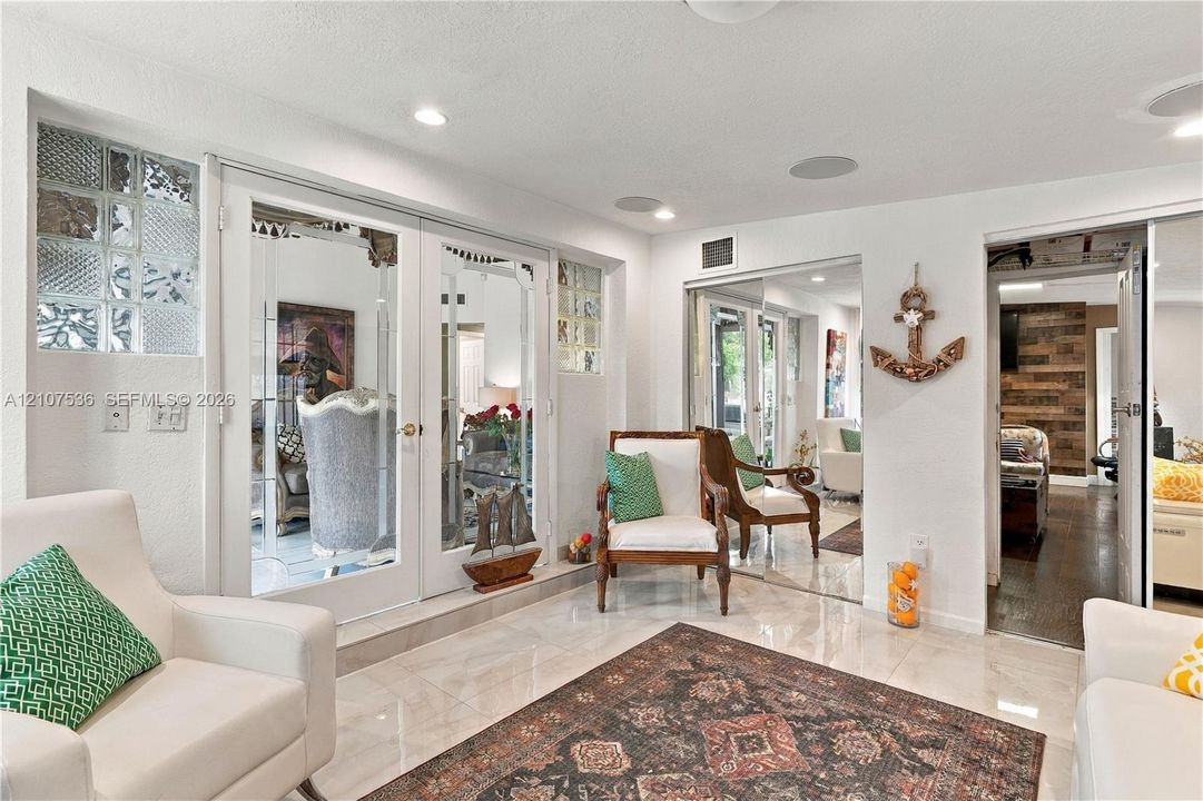 Polished stone flooring, French doors with glass panes, decorative glass block accents, and integrated ceiling speakers