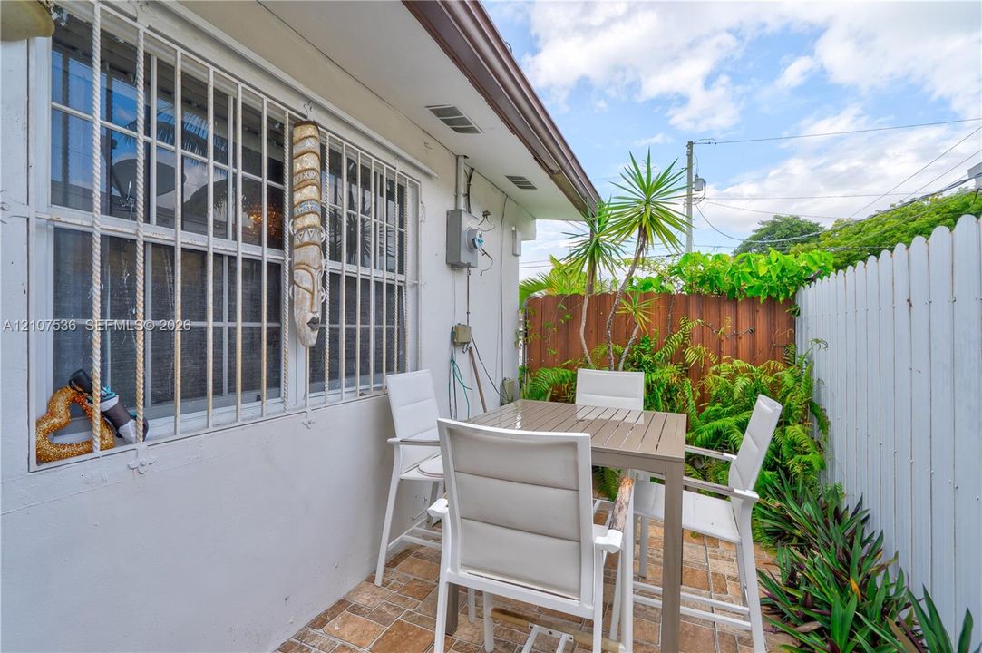 Private outdoor patio featuring earth-tone ceramic tile flooring, privacy fencing, and established perimeter landscaping