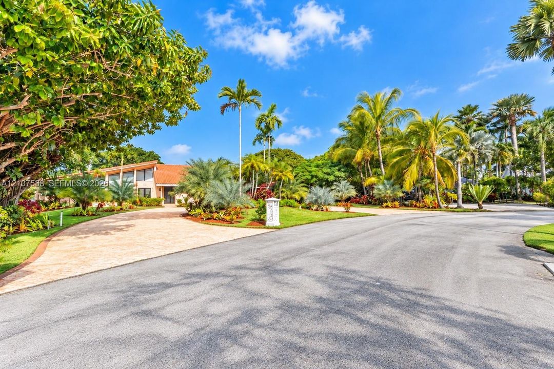 Paver stone driveway, clay tile roofing, and mature tropical landscaping