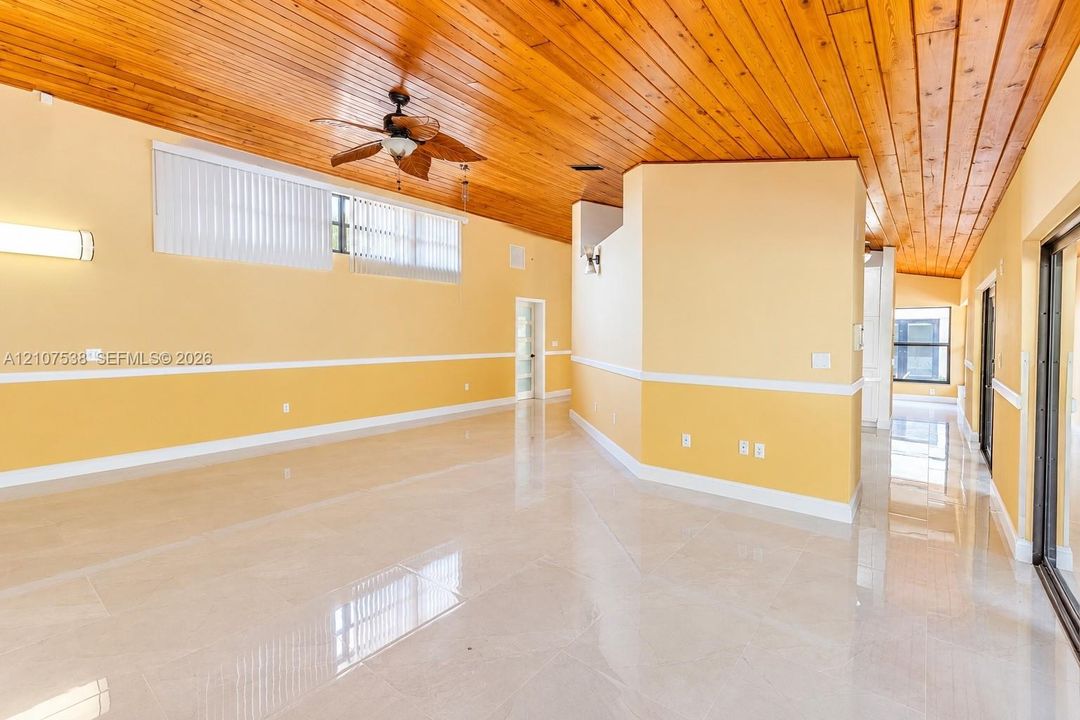 Interior featuring vaulted tongue-and-groove wood ceilings, polished tile flooring, horizontal window arrays, and a ceiling fan
