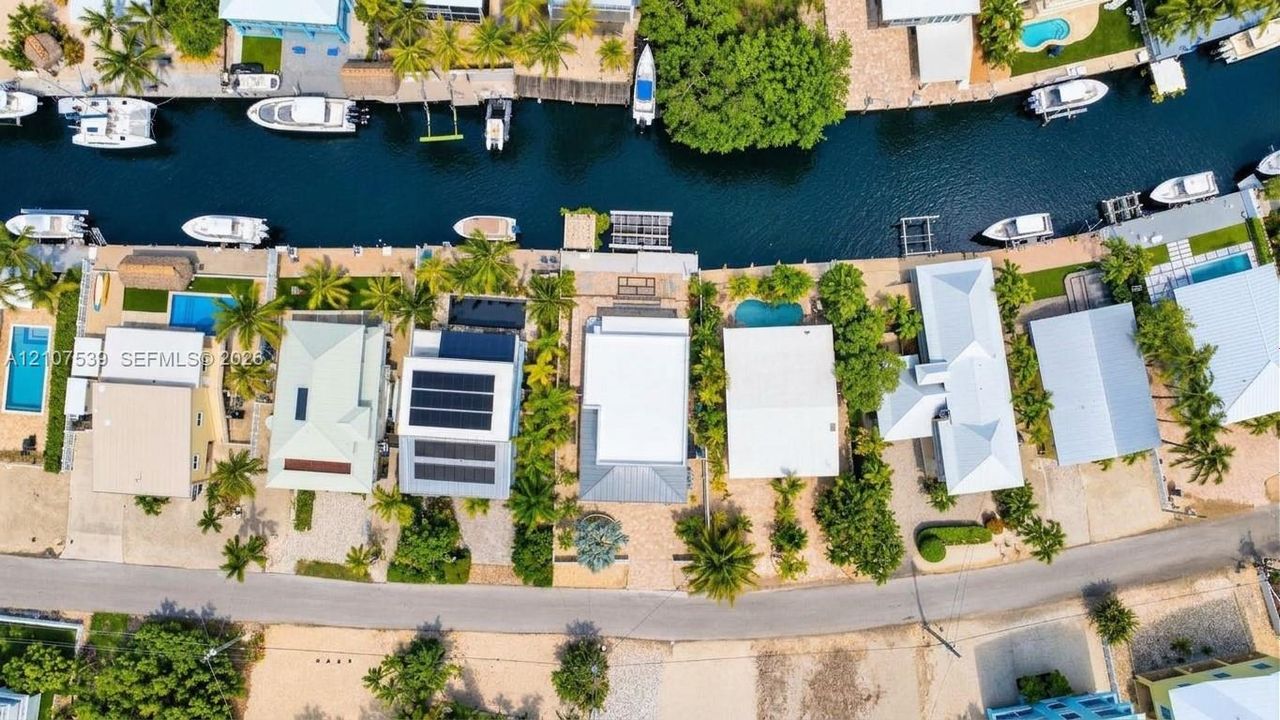 Waterfront property featuring a private boat dock, direct canal access, paved driveway, and solar panel array