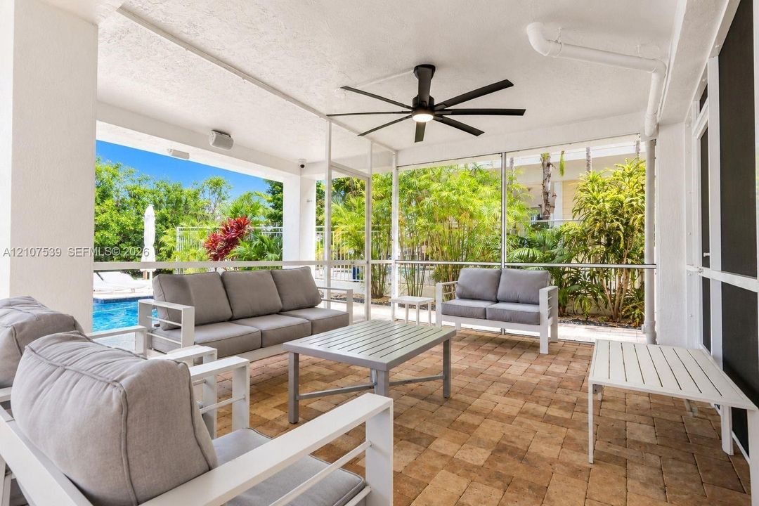Covered screened lanai featuring paver flooring, a ceiling fan with integrated lighting, and structural columns