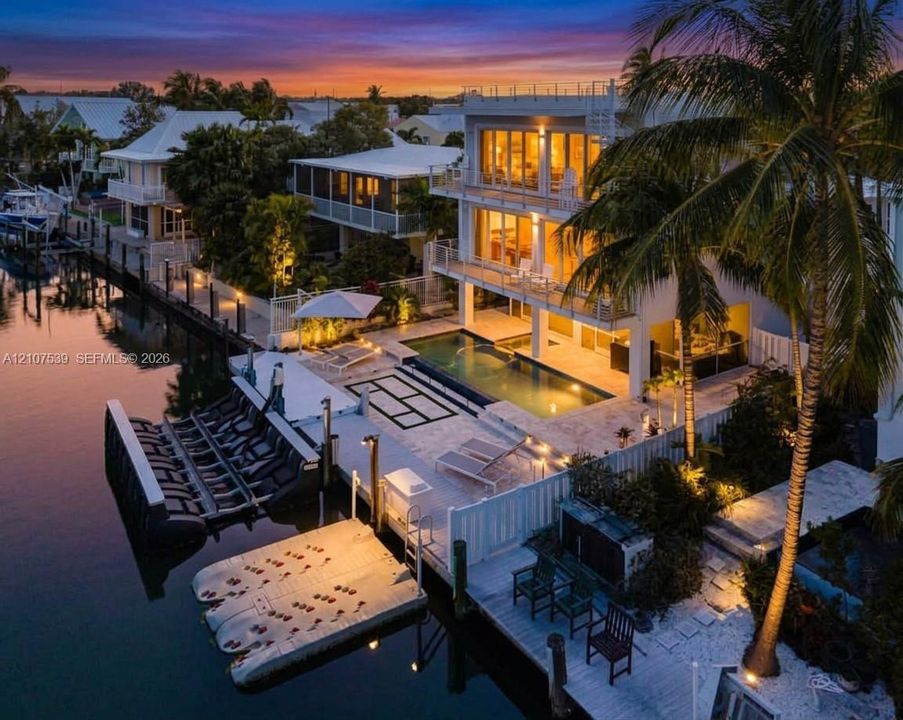 Three-story waterfront residence featuring multi-level balconies, a stone-surround swimming pool, and a private dock with boat lift