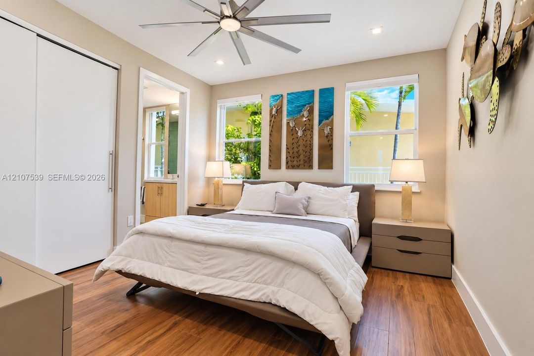 Wood-finish flooring, recessed lighting, ceiling fan, sliding closet doors, and windows with exterior greenery