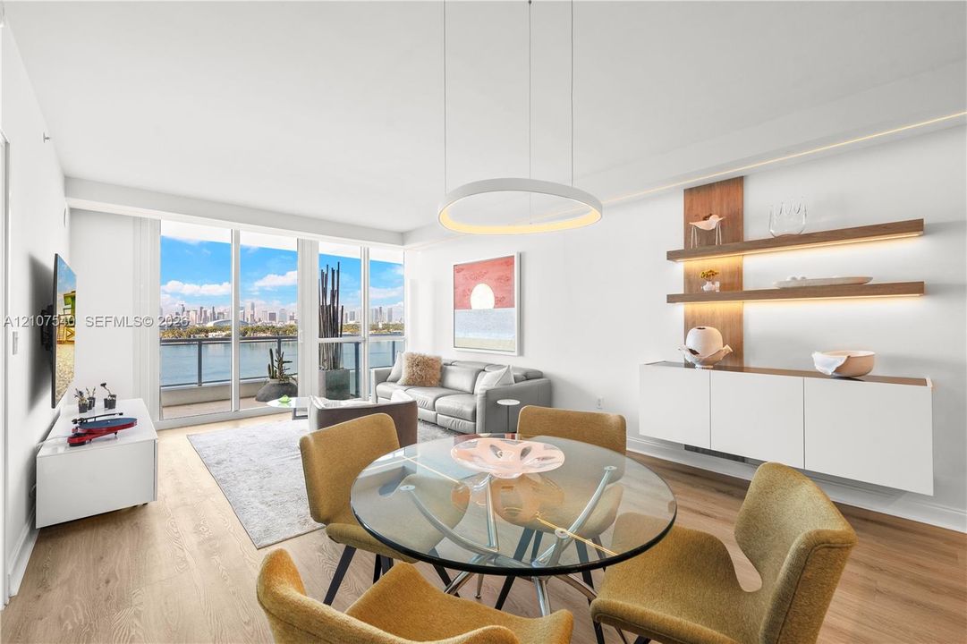 Open-concept living space featuring floor-to-ceiling windows, wood-finish flooring, modern circular LED integrated lighting built into custom soffits, and built-in floating wall shelving with integrated LED lighting