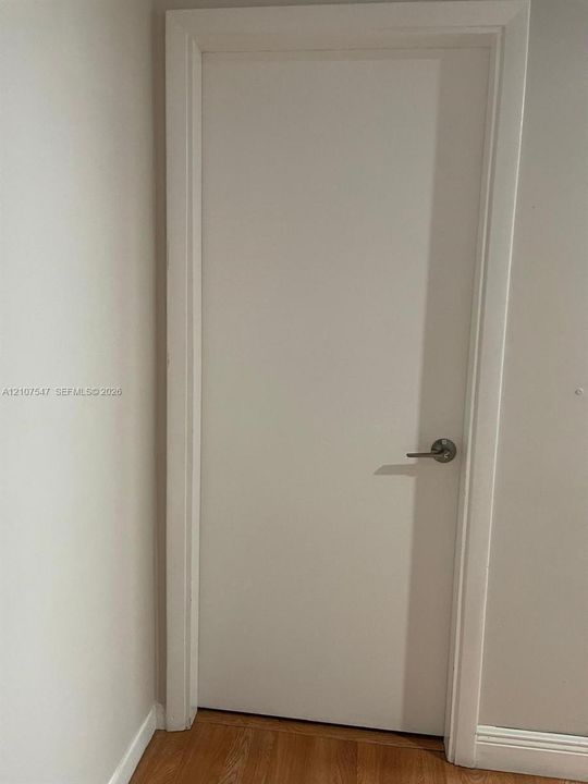 Solid-core interior door with a minimalist flat-panel design, clean white finish, and brushed nickel hardware