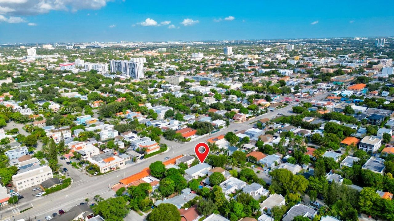 Aerial perspective of a residential property featuring mature landscaping, a swimming pool, and proximity to urban infrastructure