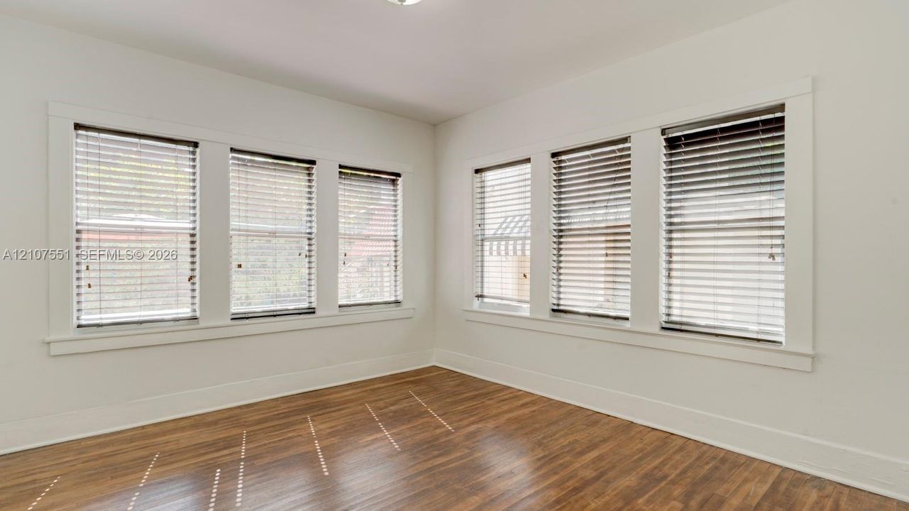 Interior space featuring wood-finish flooring, six windows with horizontal blinds, and clean-lined white trim